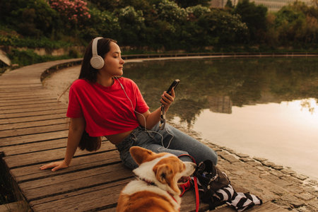 Close-up of a woman with Welsh Corgi in a park on a hot sunny day. The dog looks tired from the heat. Concept of summer walk, pet care, and companionship. Soft focus. Part of a series.の写真素材