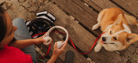 Close-up of a woman with Welsh Corgi in a park on a hot sunny day. The dog looks tired from the heat. Concept of summer walk, pet care, and companionship. Soft focus. Part of a series.の写真素材