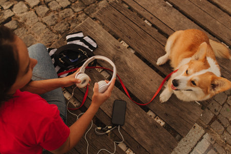 Close-up of a woman with Welsh Corgi in a park on a hot sunny day. The dog looks tired from the heat. Concept of summer walk, pet care, and companionship. Soft focus. Part of a series.の写真素材