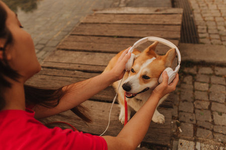 Close-up of a woman with Welsh Corgi in a park on a hot sunny day. The dog looks tired from the heat. Concept of summer walk, pet care, and companionship. Soft focus. Part of a series.の写真素材