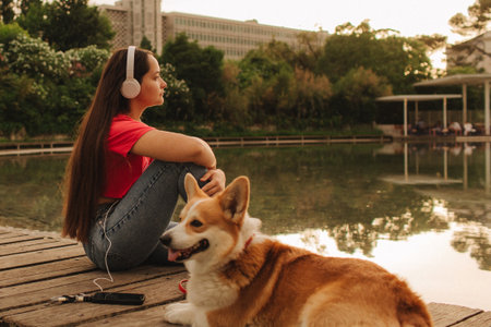 Close-up of a woman with Welsh Corgi in a park on a hot sunny day. The dog looks tired from the heat. Concept of summer walk, pet care, and companionship. Soft focus. Part of a series.の写真素材