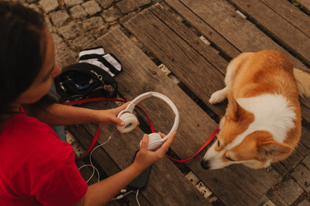 Close-up of a woman with Welsh Corgi in a park on a hot sunny day. The dog looks tired from the heat. Concept of summer walk, pet care, and companionship. Soft focus. Part of a series.の写真素材