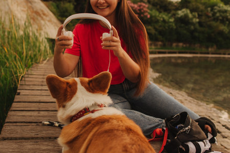 Close-up of a woman with Welsh Corgi in a park on a hot sunny day. The dog looks tired from the heat. Concept of summer walk, pet care, and companionship. Soft focus. Part of a series.の写真素材