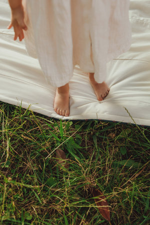 Close-up of the legs of a baby girl on the grass in a sunny park. Family bonding, early learning,...