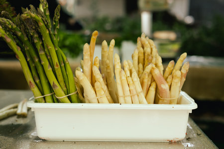 Fresh asparagus at small local urban market. Organic produce on sale at outdoor farmer market. Selling fresh crops and veggies harvest. European urban setting. Close up. Part of the series.の写真素材