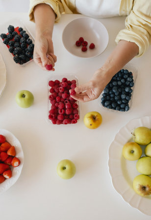 Caucasian woman preparing homemade fruit leather, slicing fresh fruit in her kitchen for a healthy snack. Part of a series on organic treats and natural living.の写真素材