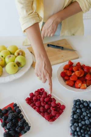 Caucasian woman preparing homemade fruit leather, slicing fresh fruit in her kitchen for a healthy snack. Part of a series on organic treats and natural living.の写真素材