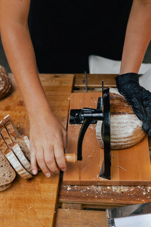 Hand-slicing craft bread on a table in a local bakery. The healthy eating and traditional bakery...
