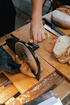 Hand-slicing craft bread on a table in a local Portuguese bakery. The healthy eating and traditional...
