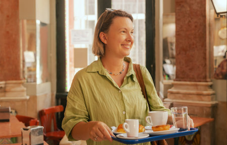 Middle age woman tries Portuguese egg tart pastry called Pastel de Nata near bakery in Lisbon. Solo tourism and travel. Part of a seriesの写真素材
