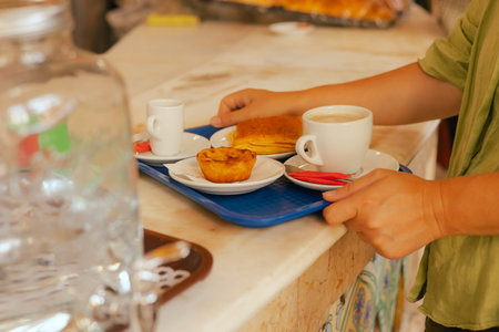 Close up middle age woman tries Portuguese egg tart pastry called Pastel de Nata with coffee near...