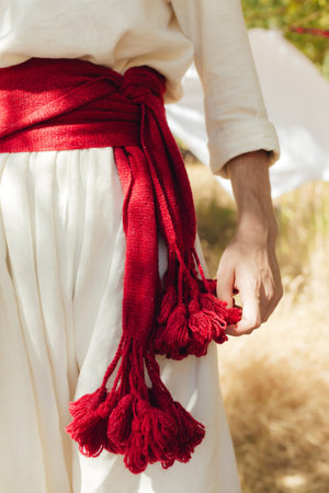 Close-up of Ukrainian traditional costume embroidered vyshyvanka blouse, woven belt kraika, folk jewelry. Ethnic festive clothing, national outfit details, cultural heritage. Part of the series.の写真素材