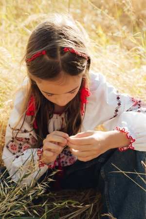 Close-up of Ukrainian girl in traditional blouse Vyshyvanka weaving a flower wreath for Ivana Kupala...