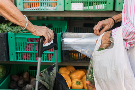 Close up of old woman's hand buying greens on the local Farmers market. Mature Female Customer Shopping At Farmers Market Stall. Close up. Part of the series.の写真素材