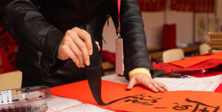 Close up of woman writing Happy New Year with Chinese calligraphy on couplets for celebration....