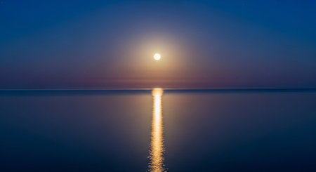 a tranquil scene of the moon reflecting on the water creating a peaceful and serene atmosphere at nightの写真素材