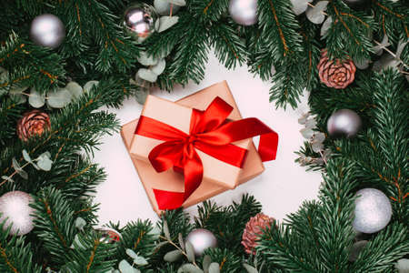 Gifts with red ribbon and branches of the pine tree with Christmas ball on the white backgroundの写真素材