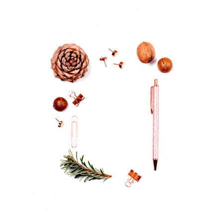 Frame made of pine cone, nuts and stationery materials on white background with place for text.の写真素材