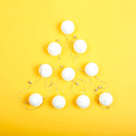 Christmas tree made of white garlsnd balls on the bright yellow background. Minimal Christmas flat layの写真素材