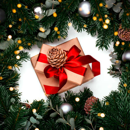 Gifts with red ribbon and branches of the pine tree with Christmas ball on the white backgroundの写真素材