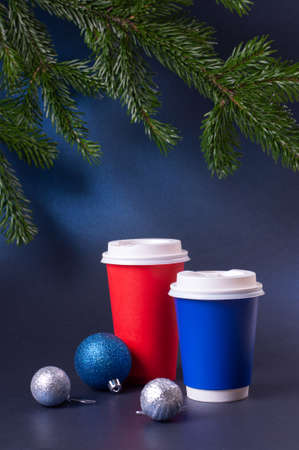 Blank blue and red to go coffee cups and pine tree branches on trendy classic blue background.の写真素材