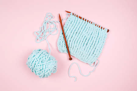 Mentol yarn ball and wodden knitting needle on light pink backgroundの写真素材