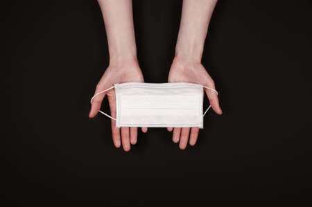 Woman hans hold madicine face mask on black backgroundの写真素材
