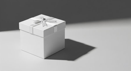 Stylish white present with a ribbon casts a long shadow on a clean surface, evoking elegance and holiday simplicity.の素材