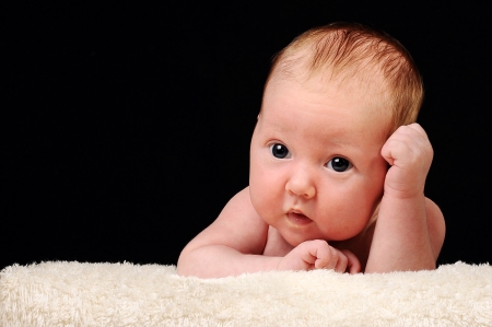 Beautiful newborn baby resting on her hands, black backgroundの写真素材