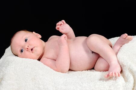 Cute newborn child laying on a white blanket, black backgroundの写真素材