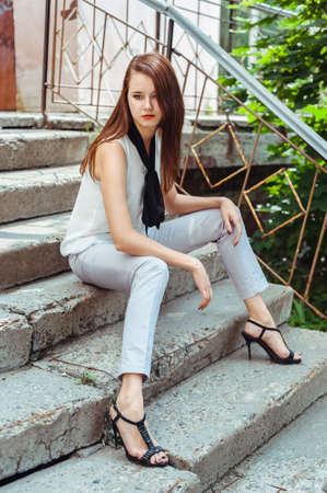 Attractive brunette girl sitting on the stone stepsの写真素材