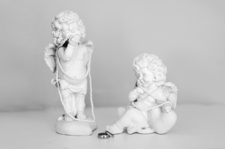 two statues of guardian angels with a beads and rings of newlywedsの写真素材