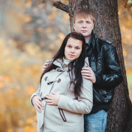 pregnant woman and her husband walking in the autumn parkの写真素材