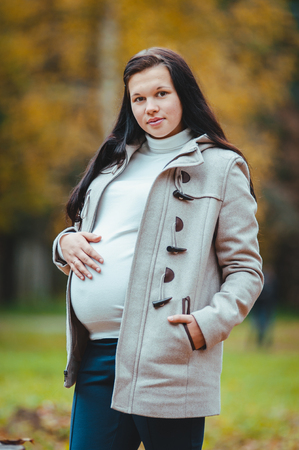beautiful pregnant woman walking in the autumn parkの写真素材