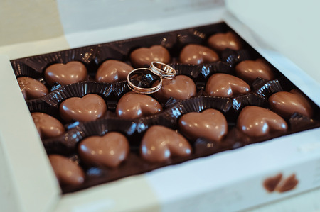 gold wedding rings and a box of chocolatesの写真素材