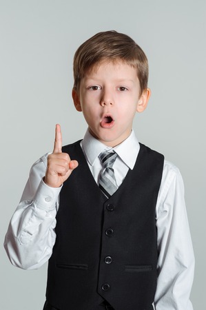 Portrait of schoolboy with idea showing finger upward. education and school conceptの写真素材