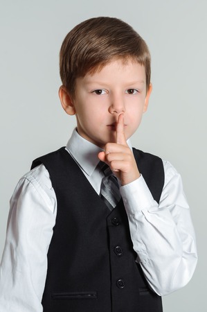 Schoolboy making sign with his finger to keep silenceの写真素材