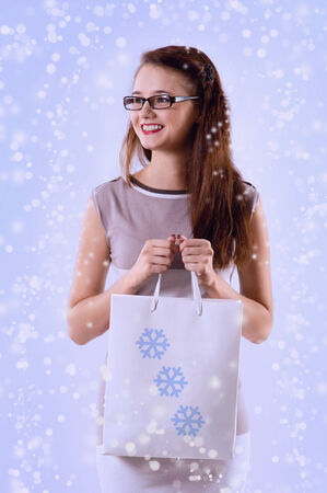 Young smiling woman in glasses with shopping bag over the Christmas background. Christmas salesの写真素材