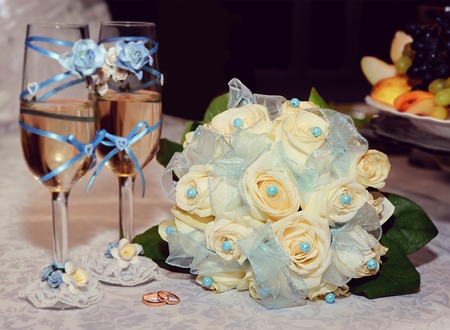 Wedding rings with bridal bouquet of white roses and glasses of champagne, selective focusの写真素材