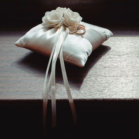 gold wedding rings on a white pillowの写真素材