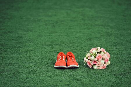 the bride's bouquet and red sneakers on the grass, runaway bride, copy spaceの写真素材