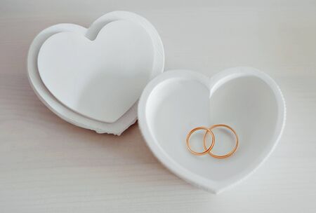 two gold wedding rings in a box in the shape of a heartの写真素材