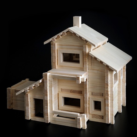 Little wooden house with natural colored toy blocks on black backgroundの写真素材