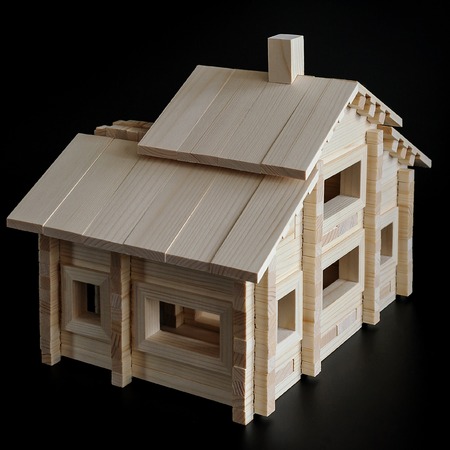 Little wooden house with natural colored toy blocks on black backgroundの写真素材
