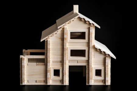 Little wooden house with natural colored toy blocks on black backgroundの写真素材