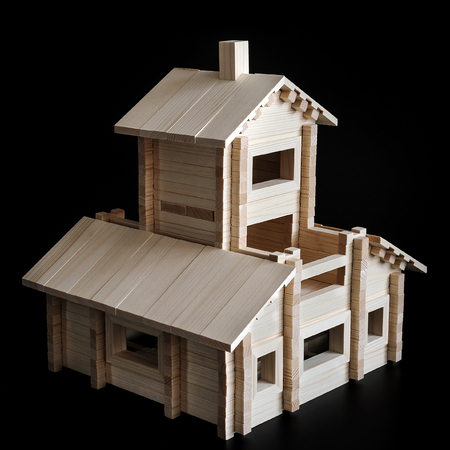 Little wooden house with natural colored toy blocks on black backgroundの写真素材