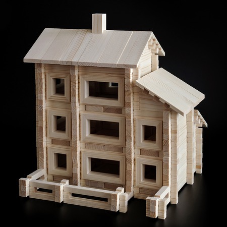 Little wooden house with natural colored toy blocks on black backgroundの写真素材