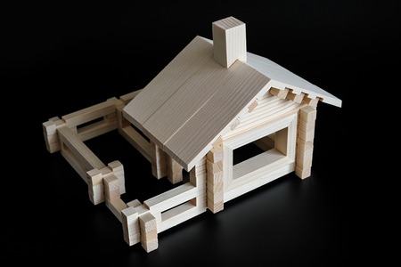 Little wooden house with natural colored toy blocks on black backgroundの写真素材