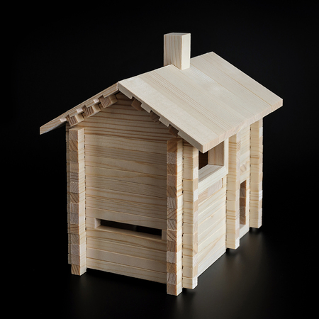 Little wooden house with natural colored toy blocks on black backgroundの写真素材