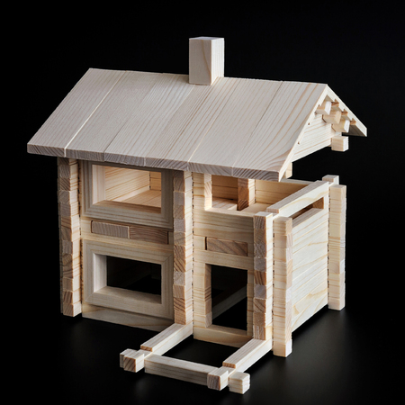 Little wooden house with natural colored toy blocks on black backgroundの写真素材